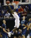 Florida forward Dorian Finney-Smith (10) shoots against UCLA forward Travis Wear (24) and UCLA forward David Wear (12) during the first half in a regional semifinal game at the NCAA college basketball tournament, Thursday, March 27, 2014, in Memphis, Tenn. (AP Photo/John Bazemore)