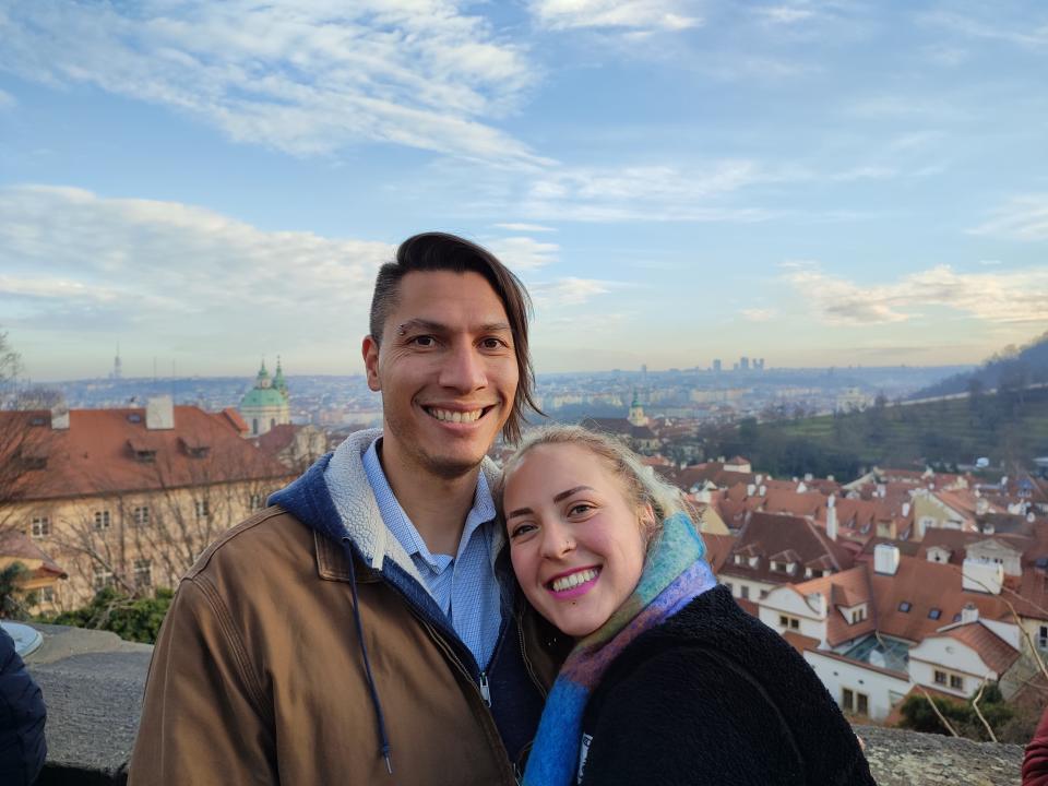 Photo of man and woman smiling at the camera with a town in the background