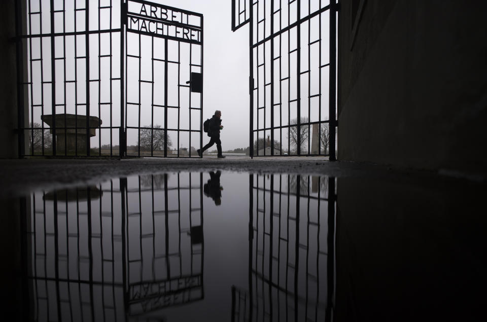 A person walks behind the gate of the Sachsenhausen Nazi death camp with the phrase 'Arbeit macht frei' (work sets you free) in Oranienburg, about 30 kilometers (18 miles) north of Berlin, Germany, Tuesday, Jan. 25, 2022. On Thursday Jan. 27, the International Holocaust Remembrance Day marks the liberation of the Auschwitz Nazi death camp on Jan. 27, 1945. (AP Photo/Markus Schreiber)