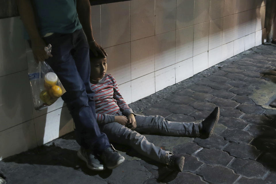 In this July 18, 2019 photo, a migrant child and his father stay together after being bused by Mexican migration authorities from Nuevo Laredo to Monterrey, Mexico. Unlike asylum seekers who wait in line, often for months, to file claims in the U.S. and then return to the Mexican border cities where they were before, all those taken to Monterrey who spoke with AP said they had crossed illegally and spent several days in U.S. detention centers before being returned with a court date. (AP Photo/Marco Ugarte)
