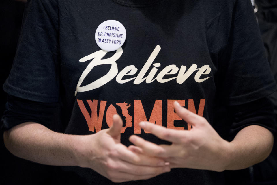 A woman wears a shirt that reads "Believe Women" with a button that reads "I Believe Dr. Christine Blasey Ford" as protesters against Supreme Court nominee Brett Kavanaugh tell their personal stories of sexual assault outside offices of Sen. Jeff Flake, R-Ariz., on Capitol Hill in Washington, Monday, Sept. 24, 2018, as the Senate begins a week of scrutiny of President Donald Trump's nominee to the high court. Judge Brett Kavanaugh's nomination to the U.S. Supreme Court has been further imperiled by a second sexual-misconduct allegation, dating to his first year at Yale University. (AP Photo/Andrew Harnik)