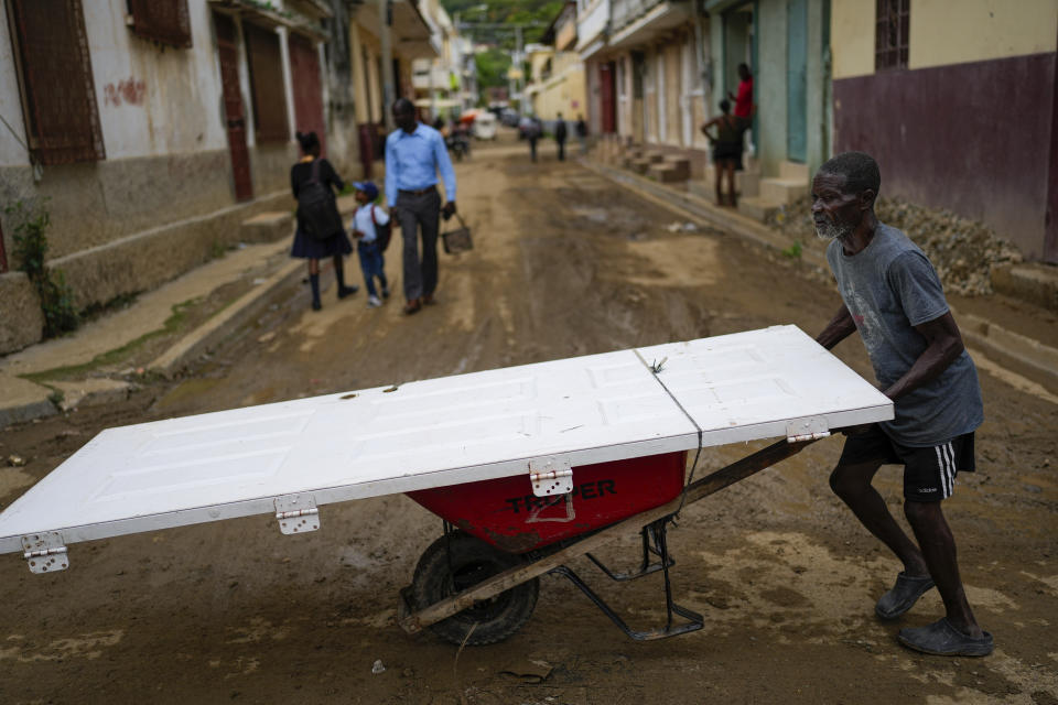 A man uses a wheelbarrow to transport a door, in Cap-Haitien, Haiti, Wednesday, April 17, 2024. (AP Photo/Ramon Espinosa)