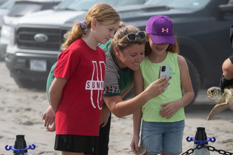 From left, Finley Whitson, her mother, Stephanie, and sister Leora look at a green sea turtle before it is released into the sea at Padre Balli Park on Thursday, Dec. 29, 2022.
