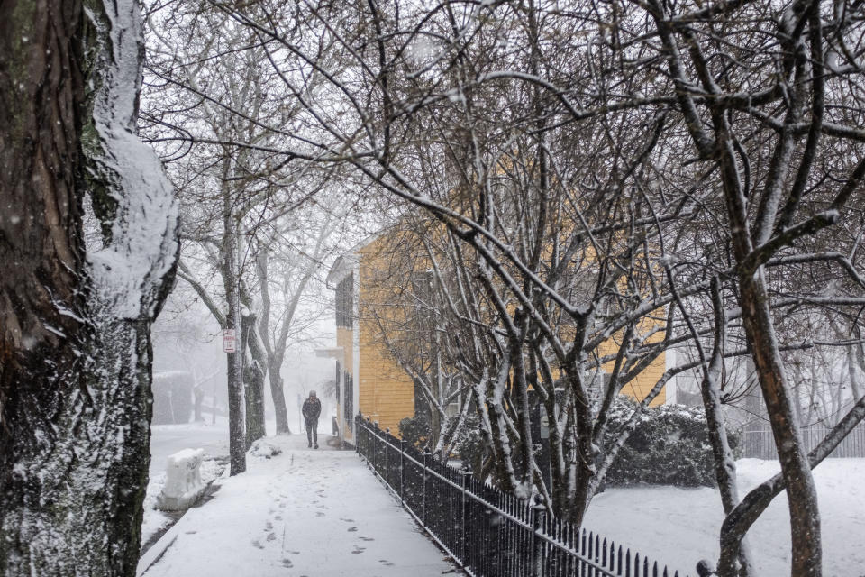 A pedestrian walks along a snow-covered sidewalk, Sunday, Jan. 7, 2024, in Providence, R.I. A major winter storm bringing heavy snow and freezing rain to some communities spread across New England on Sunday morning, sending residents scurrying to pull out their shovels and snowblowers to clear sidewalks and driveways. (AP Photo/David Goldman)