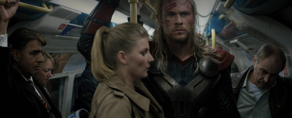 Chris Hemsworth dressed as Thor standing in a crowded subway car with other passengers