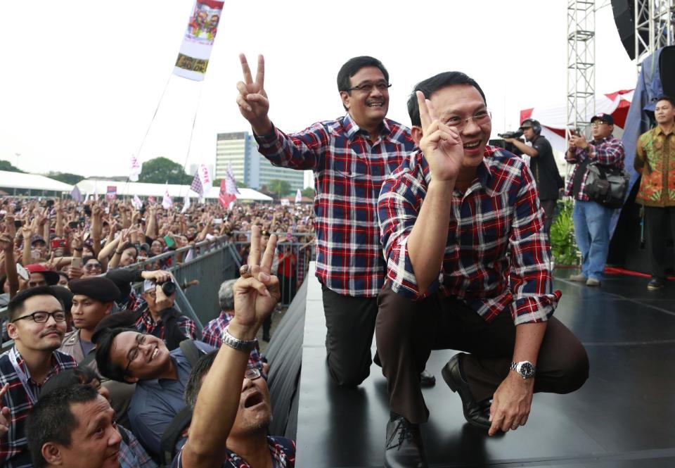 In this Saturday, Feb. 11, 2017 photo, incumbent Jakarta Governor Basuki Tjahaja Purnama, right, and his deputy and also running mate Djarot Saiful Hidayat pose for photographers as they attend a campaign rally in Jakarta, Indonesia. Purnama, popularly known as "Ahok", the first ethnic Chinese governor of Jakarta and the first Christian in more than half a century, had seemed unassailably popular until the accusation of blasphemy, a criminal offense in Indonesia, surfaced in September. Protests against him in November and December, organized by hard-line Islamic groups, drew hundreds of thousands to Jakarta's streets and shook the centrist-minded government of President Joko "Jokowi" Widodo. (AP Photo/Dita Alangkara)