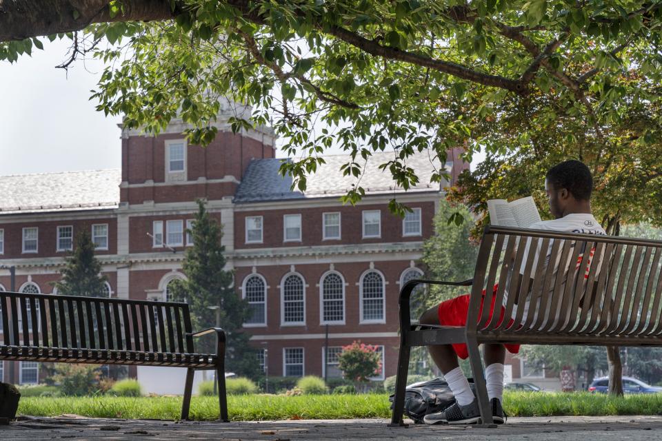 FILE - With the Founders Library in the background, a young man reads on Howard University campus July 6, 2021, in Washington. Nationwide, American colleges and universities saw a 4% annual increase in international students this fall, according to survey results released Monday, Nov. 15, by the Institute of International Education. But that follows a decrease of 15% last year, the steepest decline since the institute began publishing data in 1948. (AP Photo/Jacquelyn Martin, File)