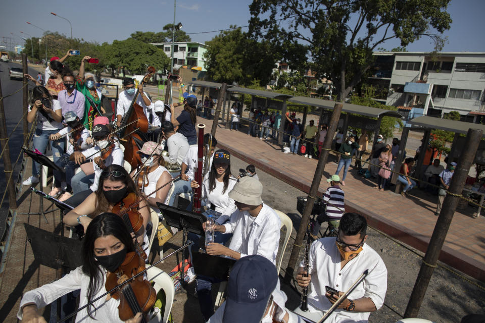 Wearing masks to curb the spread of the new coronavirus, musicians join pianist, composer and conductor Jose Agustin Sanchez on the bed of an eighteen-wheeler truck for a musical tour called "Musical Disinfection," in Barquisimeto, Venezuela, Thursday, March 4, 2021. Sanchez, who last year started playing what he calls his "Musical Vaccine" for COVID patients, is now joined by other musicians as they ride through the city playing his original compositions for anybody that wants to listen. (AP Photo/Ariana Cubillos)