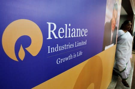 FILE PHOTO: A woman walks past a poster of Reliance Industries installed outside the venue of the company's annual general meeting in Mumbai