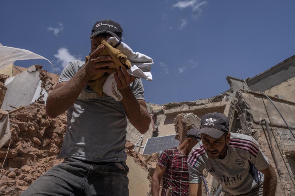 Soufiane Aarrach, a la izquierda, llora al encontrar ropa que perteneció a un hermano que murió en el terremoto, cerca de la histórica mezquita de Tinmel, en la cordillera del Atlas de Marruecos, el viernes 15 de septiembre de 2023. (Nariman El-Mofty/The New York Times)