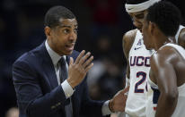 FILE - Connecticut head coach Kevin Ollie, left, talks with Connecticut's Terry Larrier and Christian Vital, right, during an NCAA college basketball game, Wednesday, Feb. 7, 2018, in Storrs, Conn. An independent arbiter has ruled that UConn improperly fired former men's basketball coach Kevin Ollie and must pay him more than $11 million, Ollie's lawyer said Thursday, Jan. 20, 2022. (AP Photo/Jessica Hill, File)