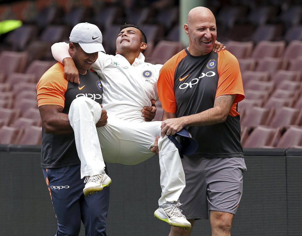 India's Prithvi Shaw, center, is carried by support staff after rolling his ankle while attempting a catch during their tour cricket match against Cricket Australia XI in Sydney, Friday, Nov. 30, 2018. (AP Photo/Rick Rycroft)