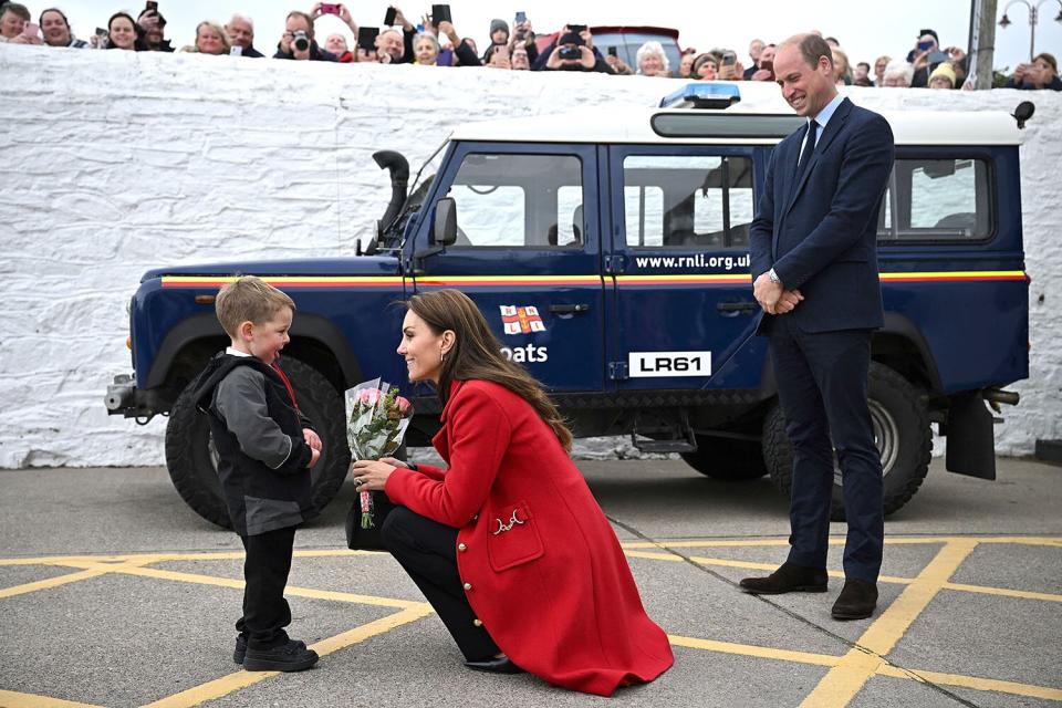 Prince William, Prince of Wales (R) watches as his wife Britain's Catherine, Princess of Wales is presented with a posy of flowers by four-year-old Theo Crompton during their visit to the RNLI (Royal National Lifeboat Institution) Holyhead Lifeboat Station in Anglesey, north west Wales