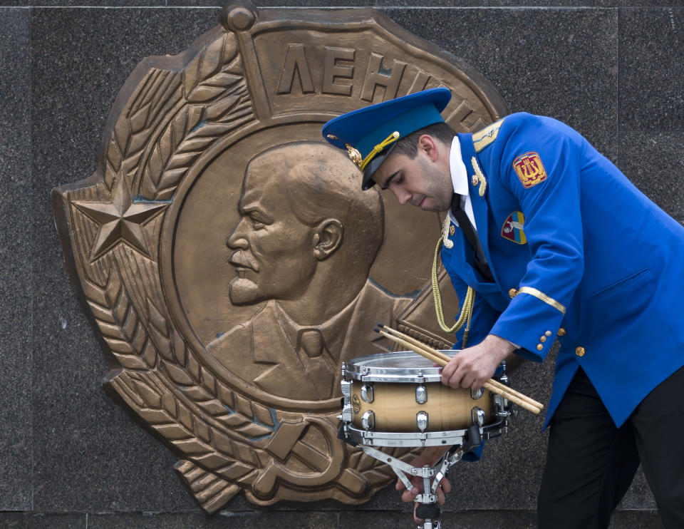 A member of a military band handles a drum, backdropped by a depiction of Soviet revolutionary leader Vladimir Lenin, before Victory Day celebrations in Odessa, Ukraine, Friday, May 9, 2014. In the Black Sea port of Odessa, which last week was rocked by violent clashes between pro-Russian forces and supporters of the central government that left nearly 50 people died, the local governor issued an order banning public display of Russian flags. (AP Photo/Vadim Ghirda)