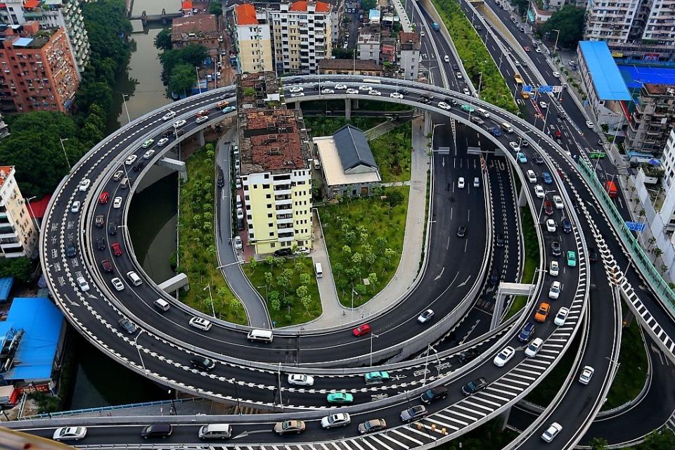 Aerial view of a multi-level spiral interchange tightly wrapping around a building with active traffic