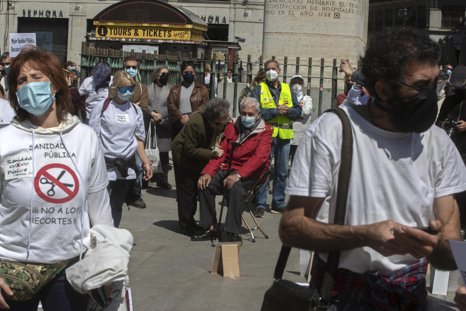 A man sits down during a protest in the central Puerta del Sol to protect the national health service during and after the pandemic, in Madrid, Spain, Saturday, April 17, 2021. Spanish Prime Minister Pedro Sanchez says he is "very hopeful" that Spain can come up with its own COVID-19 vaccine by the end of the year. (AP Photo/Paul White)