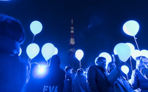 People hold balloons during the count down event at the Prince Park Tower Tokyo hotel - Credit: Getty