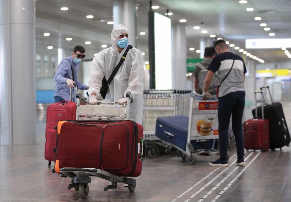 People who have arrived from New York City on an Aeroflot - Russian Airlines flight, carry their luggage at the arrivals area of Sheremetyevo International Airport. (Photo by Sergei Bobylev\TASS via Getty Images)