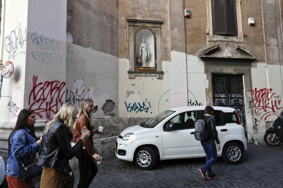 People walk past a church wall covered with graffiti in Rome, Thursday, Nov. 15, 2018. Rome’s monumental problems of garbage and decay exist side-by-side with Eternal City’s glories. (AP Photo/Gregorio Borgia)