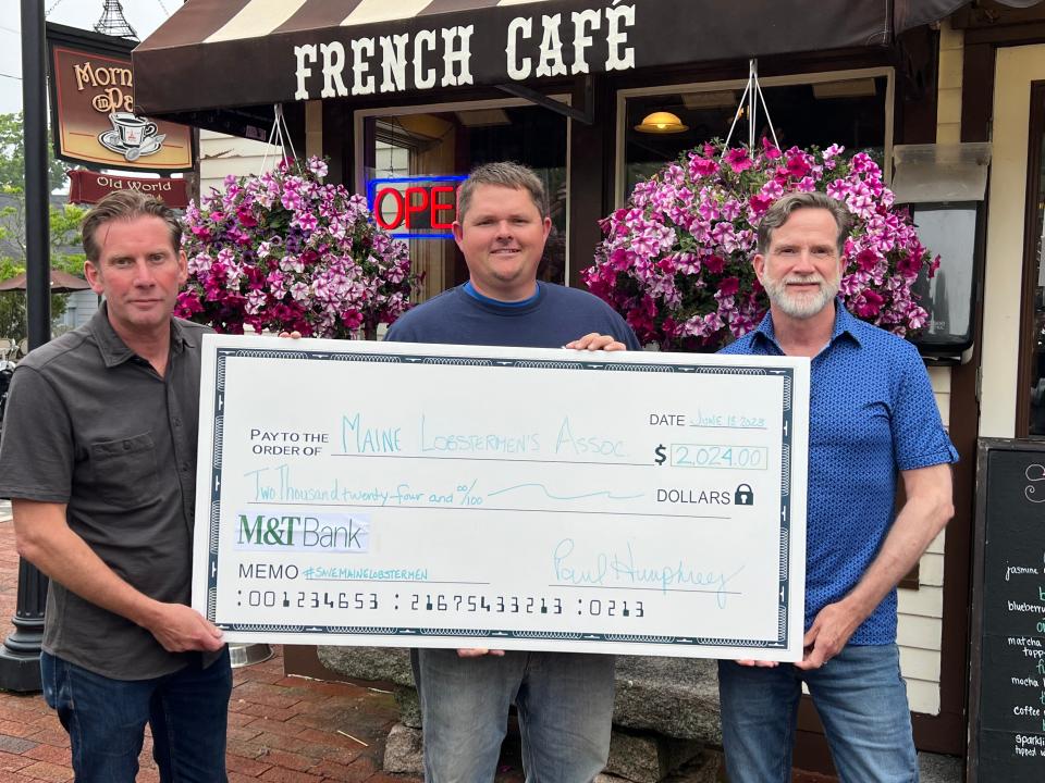 Mornings in Paris owner Paul Humphrey, left, and manager John Nickulas, right, present a check to local lobsterman and Maine Lobstermen's Association board member Chris Welch. Humphrey raised the money through sales of his specially blended Save Maine Lobstermen Coffee.