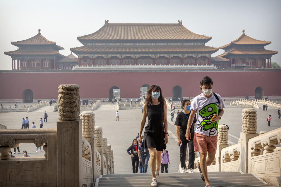 Visitors wearing face masks to protect against the new coronavirus walk through the Forbidden City in Beijing, Friday, May 1, 2020. The Forbidden City reopened beginning on Friday, China's May Day holiday, to limited visitors after being closed to the public for more than three months during the coronavirus outbreak. (AP Photo/Mark Schiefelbein)
