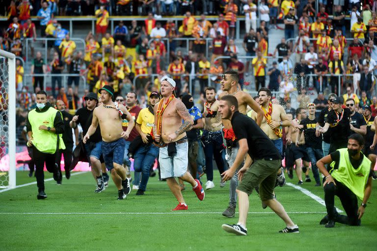 Hinchas de Lens, de Francia, invaden la cancha para buscar a los simpatizantes de Lille durante el encuentro entre ambos por la Ligue 1 de Francia.