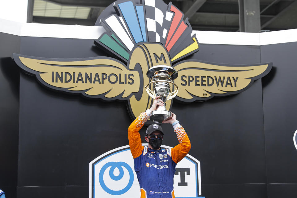 Race driver Scott Dixon, of New Zealand, celebrates with the trophy after winning the IndyCar auto race at Indianapolis Motor Speedway in Indianapolis, Saturday, July 4, 2020. (AP Photo/Darron Cummings)