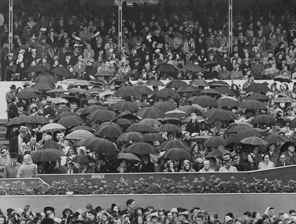 Spectators, some sheltering beneath umbrellas, watching the Coronation procession of Elizabeth II.<span class="copyright">Fox Photos/Hulton Archive/Getty Images</span>