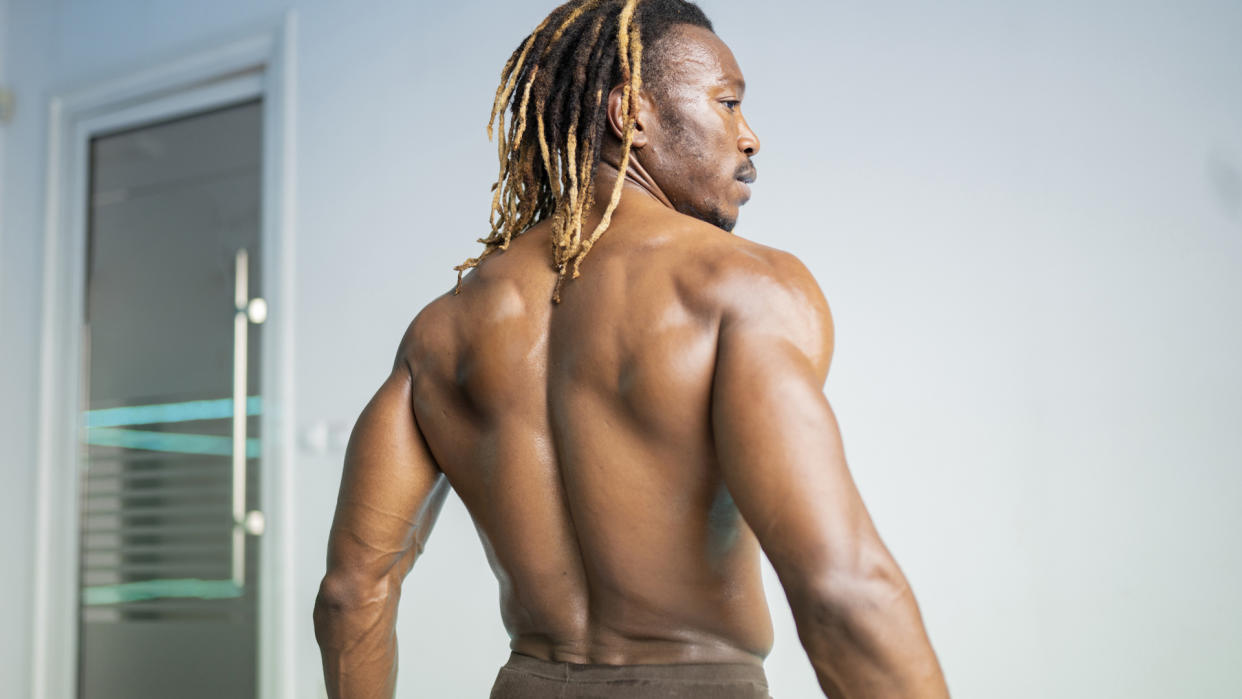  Muscular man with afro hairstyle facing away from the camera displaying his strong back muscles. 