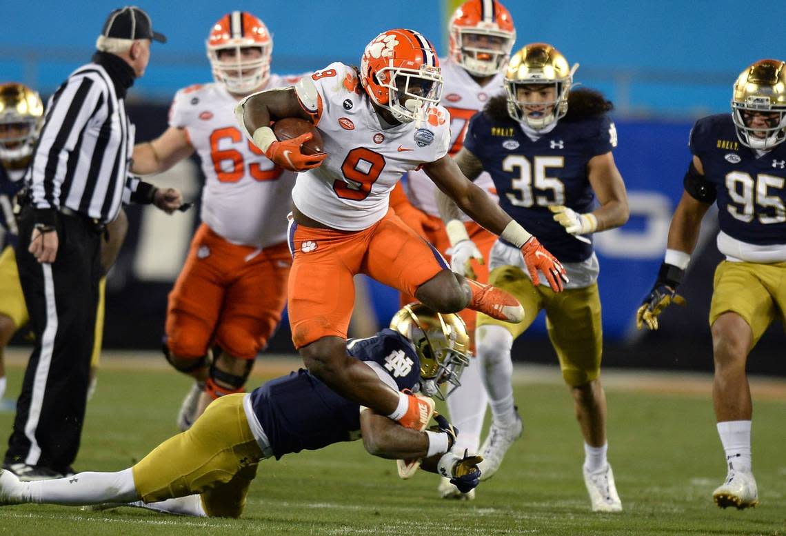 Clemson Tigers running back Travis Etienne leaps over a Notre Dame defender during third quarter action of the ACC Championship game. Clemson defeated Notre Dame 34-10 to win the championship at Bank of America Stadium in Charlotte, NC on Saturday, December 19, 2020. Jeff Siner/jsiner@charlotteobserver.com