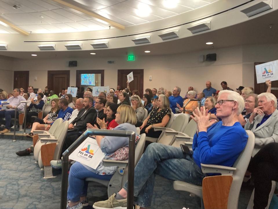 Supporters of a ballot question to raise Pueblo's lodging tax to pay for childcare wave signs in city council chambers on August 14, 2023.
