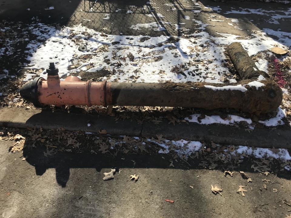 A fire hydrant on its side, showing an extended curved pipe extending from it