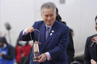 Tokyo 2020 Olympics chief Yoshiro Mori carries the Olympic flame during the Flame Arrival Ceremony at Japan Air Self-Defense Force Matsushima Base in Higashimatsushima in Miyagi Prefecture, north of Tokyo, Friday, March 20, 2020. The Olympic flame from Greece arrived in Japan even as the opening of the the Tokyo Games in four months is in doubt with more voices suggesting the games should to be postponed or canceled because of the worldwide virus pandemic. (AP Photo/Eugene Hoshiko)