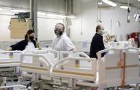 Workers add the final touches to a hospital bed being assembled at the Linet factory in Slany, Czech Republic, Monday, Oct. 19, 2020. A Czech hospital bed maker with a full order book received one more order that was impossible to turn down. The company was approached by Prime Minister Andrej Babis to deliver beds for a military field hospital for 500 COVID-19 patients, to be built this week in Prague. (AP Photo/Petr David Josek)