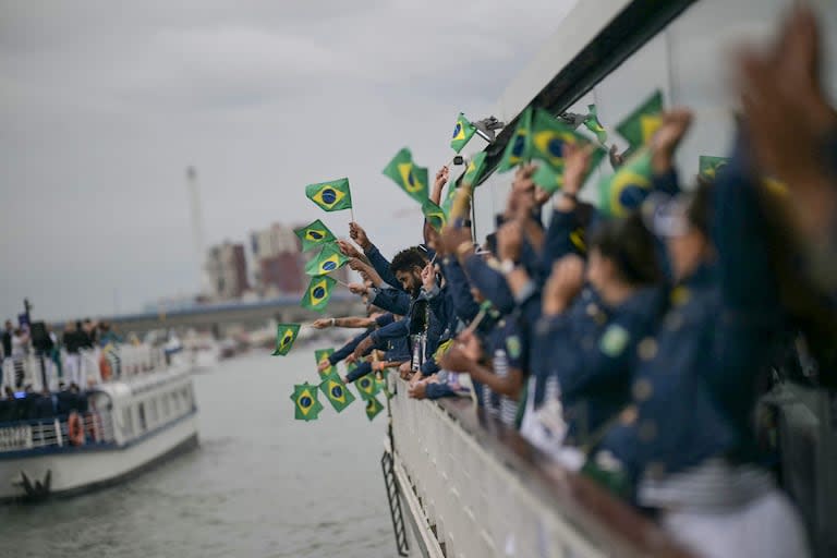 Los atletas de la delegación de Brasil ondean banderas brasileñas mientras navegan en un barco por el río Sena
