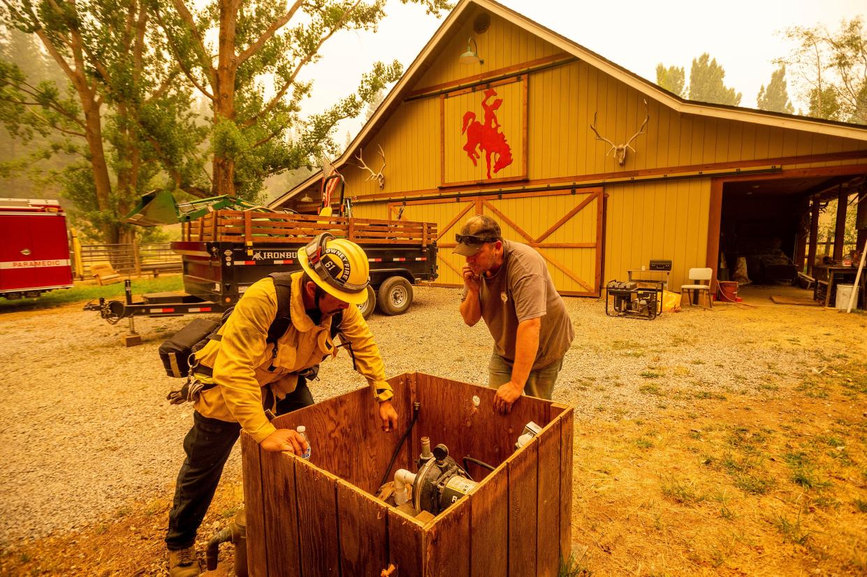 Jesse Ackley and firefighter Sergio Zavala examine a water pump while preparing for the Dixie Fire's approach in Plumas County, Calif. on Sunday, July 25, 2021. Officials expanded evacuation orders earlier in the day.
