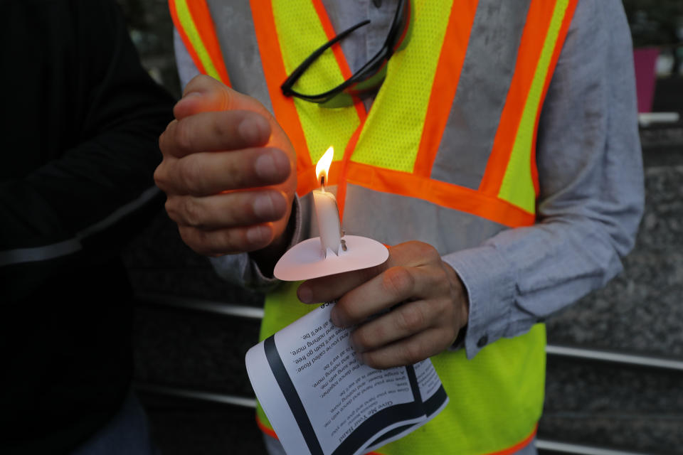 A worker holds a candle during a candlelight vigil outside city hall for deceased and injured workers from the Hard Rock Hotel construction collapse Sat., Oct., 12, in New Orleans, Thursday, Oct. 17, 2019. The vigil was organized by various area labor groups. (AP Photo/Gerald Herbert)