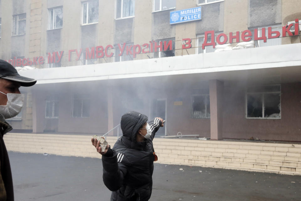 A pro-Russian man throws a stone during the mass storming of a police station in the eastern Ukrainian town of Horlivka on Monday, April 14, 2014. Text on the building reads: "Horlivka's police". Several government buildings has fallen to mobs of Moscow loyalists in recent days as unrest spreads across the east of the country. (AP Photo/Efrem Lukatsky)