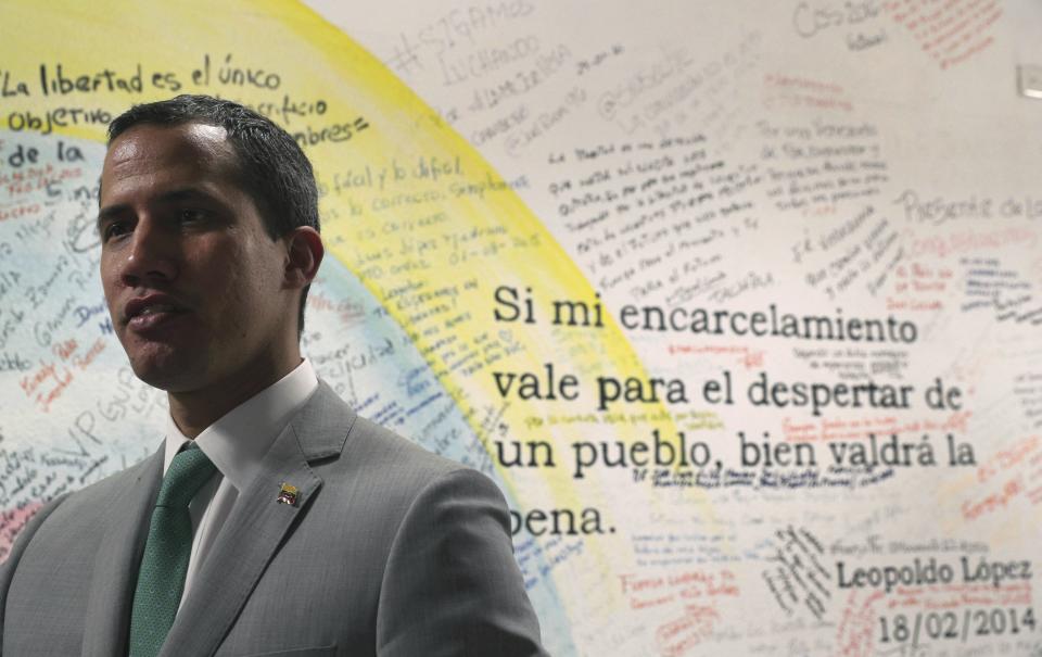 Venezuela's opposition leader Juan Guaidó, who declared himself the interim-president of Venezuela, stands next to a mural that displays a quote by Leopoldo Lopez, founder of the Popular Will party, that reads in Spanish: "If my imprisonment is worth the awakening of the people, then it was worth it," at party headquarters in Caracas, Venezuela, Friday, May 10, 2019. The 35-year-old national assembly president, who the U.S. and 50 other countries recognize as Venezuela's rightful leader, sat for an interview with The Associated Press at his party's headquarters on Friday. (AP Photo/Martin Mejia)