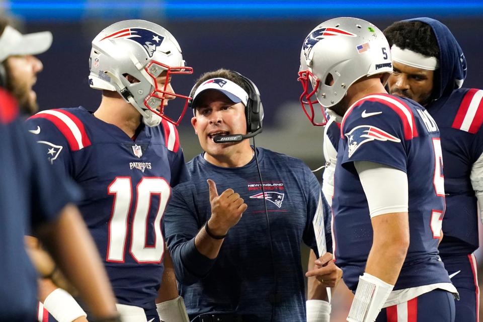 New England Patriots quarterback Mac Jones (10) listens to offensive coordinator Josh McDaniels during Thursday's preseason game against the Washington Football Team in Foxborough, Mass. At back right is Patriots quarterback Cam Newton.