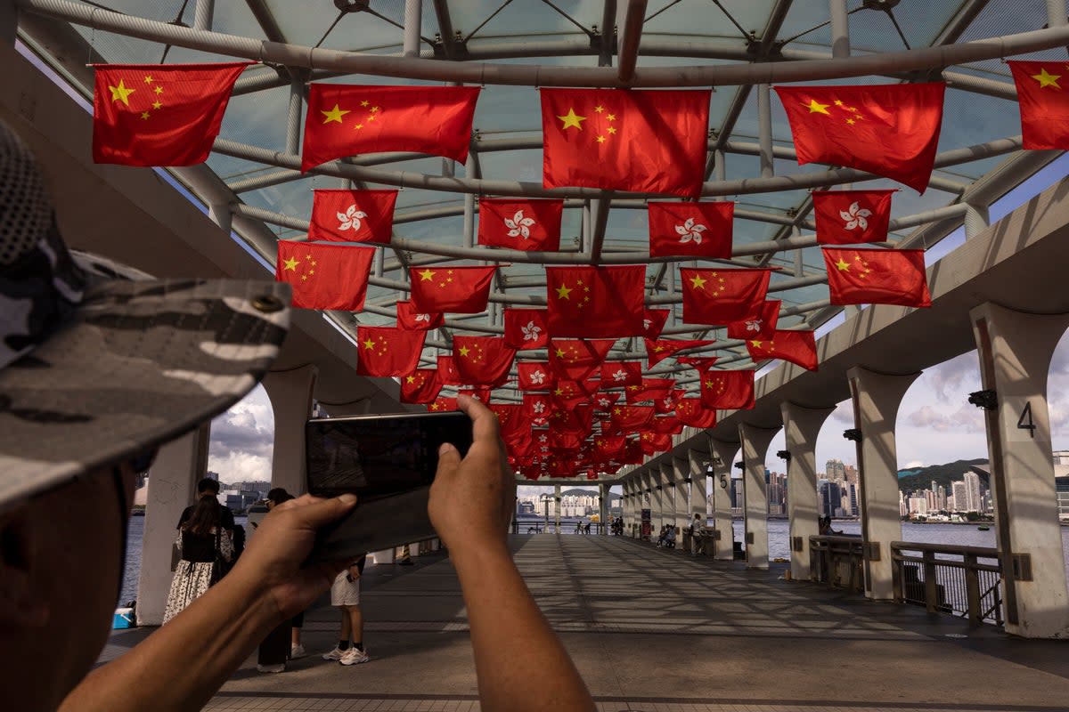 File. Mainland Chinese tourists take photographs as Chinese and Hong Kong flags are strung to mark the 26th anniversary of the city’s handover from Britain to China in Hong Kong, on June 27, 2023. A Japanese journalist was barred from entering Hong Kong without a clear reason and was sent back to his country, a Japanese newspaper reported Friday, 30 June 2023 raising concerns over the city’s shrinking press freedoms (Associated Press)