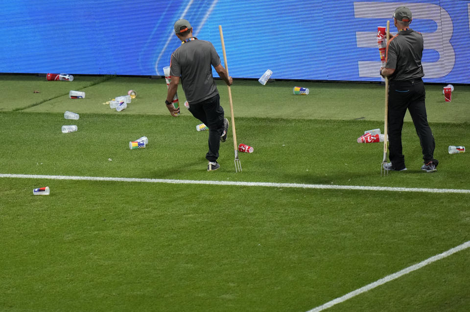 Ground staff clear up plastic cups and glasses that had been thrown onto the pitch during the Group B match between Croatia and Italy at the Euro 2024 soccer tournament in Leipzig, Germany, Monday, June 24, 2024. (AP Photo/Sergei Grits)