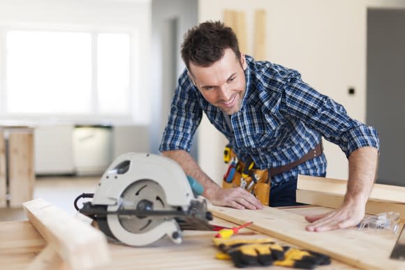 Carpenter cuts wood using table saw.