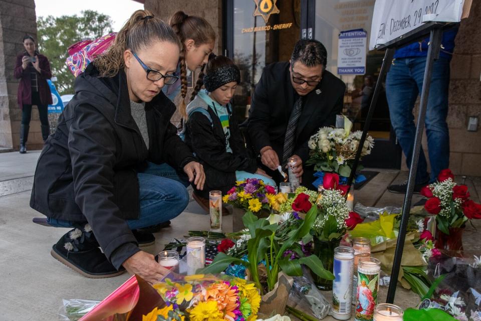 Mayor Chris Barajas with his family lights a candle at a makeshift memorial of flowers and candles for Deputy Isaiah Cordero