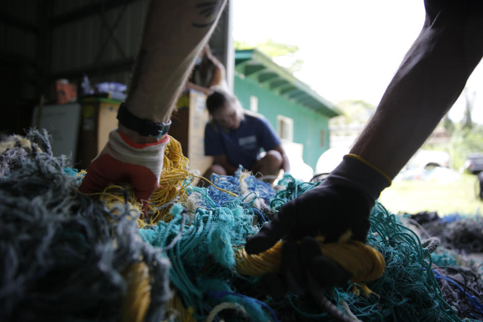 Hawaii Pacific University master's student Drew McWhirter, foreground, and Raquel Corniuk, a research technician at the university's Center for Marine Debris Research, pull apart a massive entanglement of ghost nets on Wednesday, May 12, 2021 in Kaneohe, Hawaii. The two are part of a study that is attempting to trace derelict fishing gear that washes ashore in Hawaii back to the manufacturers and fisheries that it came from. (AP Photo/Caleb Jones)