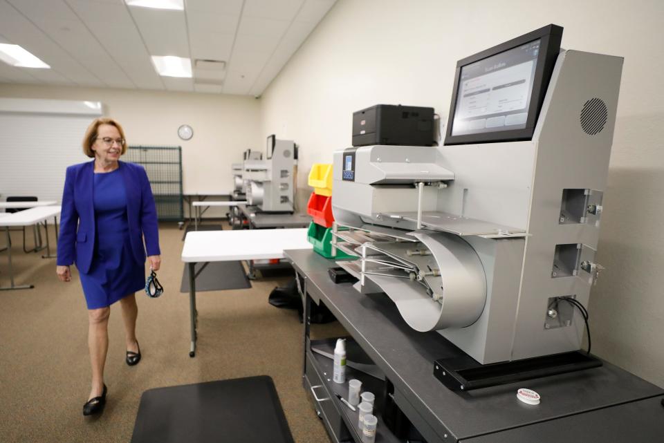 Lori Edwards, Polk County supervisor of elections, walks past the high-speed scanners that are used to count the vote by mail ballots in 2020.