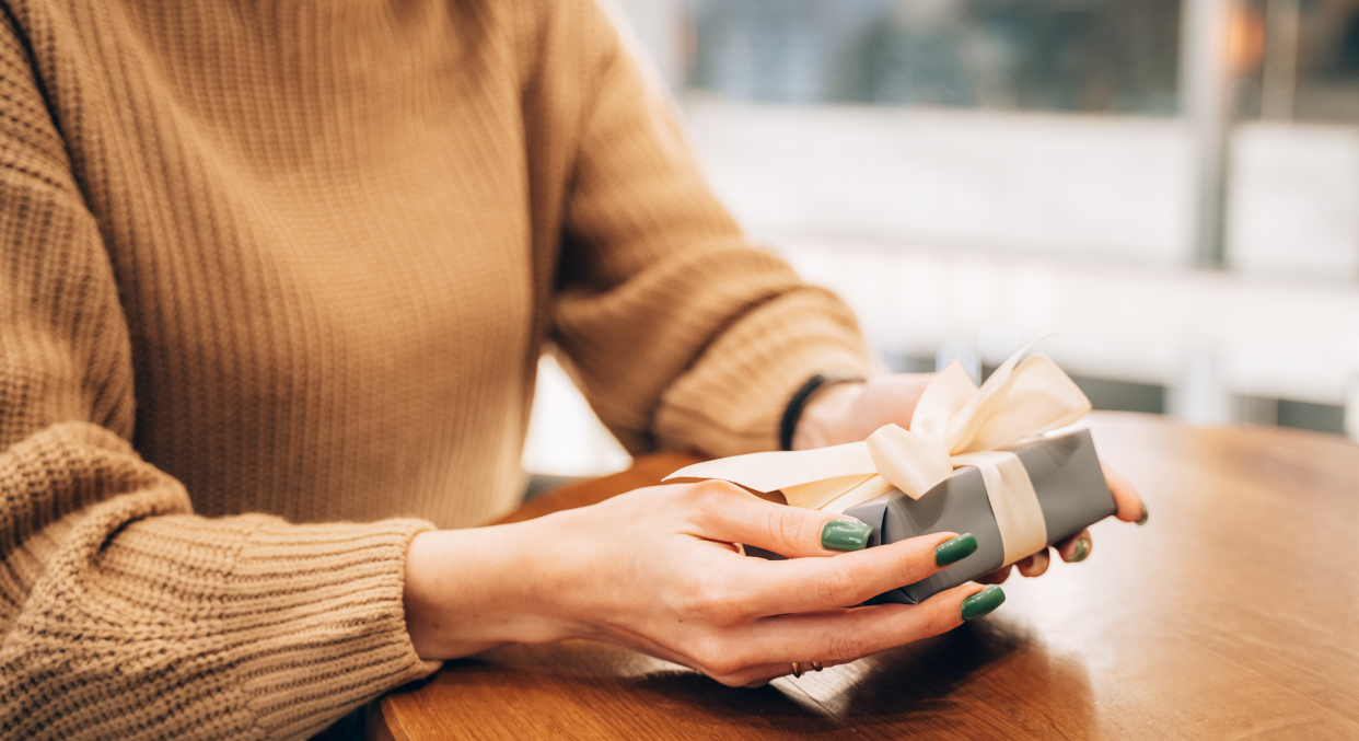 Woman with a December birthday sat at table holding unopened present