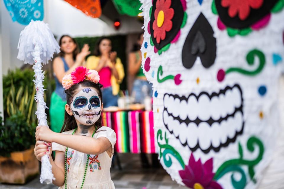 Día de los Muertos celebrations in Mexico are adapting and fusing with Halloween in interesting ways. <a href="https://www.gettyimages.com/detail/photo/girl-hitting-pi%C3%B1ata-during-a-day-of-the-death-royalty-free-image/1653070912?phrase=day+of+the+dead&adppopup=true" rel="nofollow noopener" target="_blank" data-ylk="slk:FG Trade Latin/ Collection E+ via Getty Images;elm:context_link;itc:0;sec:content-canvas" class="link ">FG Trade Latin/ Collection E+ via Getty Images</a>