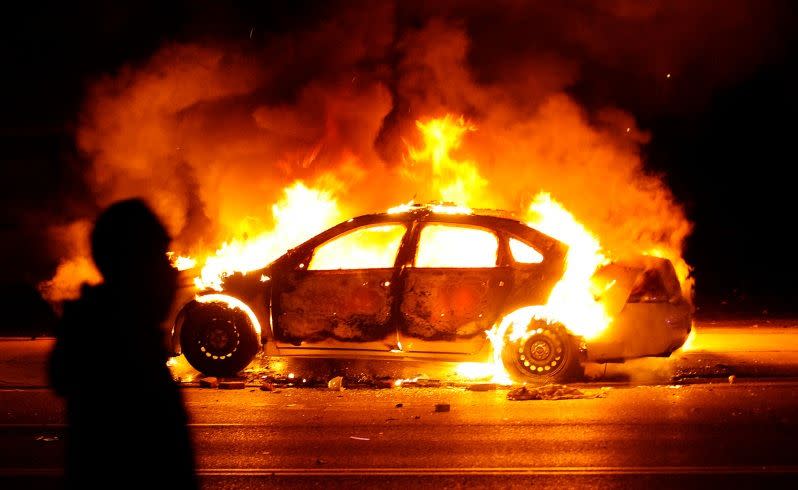 A protester walks by a St. Louis County police car that was set on fire. Picture: Los Angeles Times/TNS