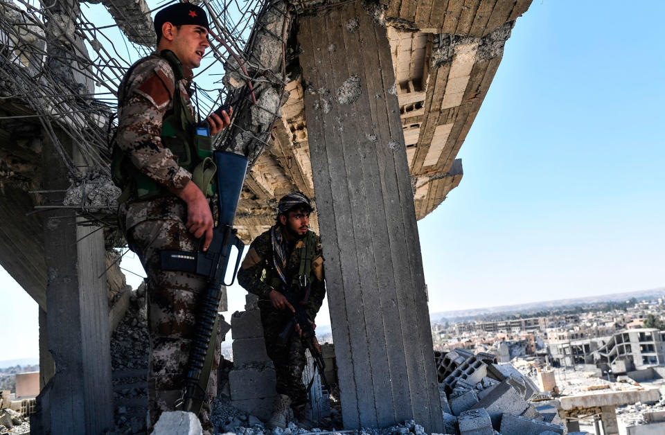 <p>Members of the Syrian Democratic Forces (SDF), backed by US special forces, walk on a building near Raqa’s central hospital as they clear the last positions on the frontline on Oct. 16, 2017 in the Islamic State (IS) group jihadists crumbling stronghold. (Photo: Bulent Kilic/AFP/Getty Images) </p>